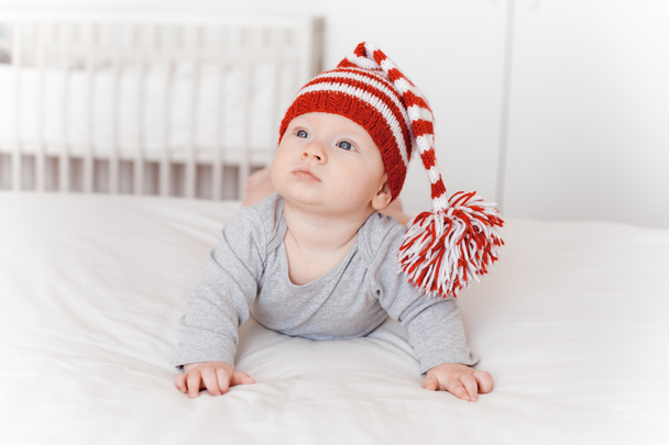 portrait of cute infant child in knitted hat lying on bed - Fotografie, Obrázek