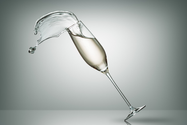 spilling champagne from falling glass on white - 写真・画像