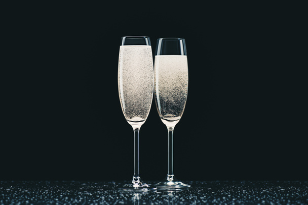 zwei Gläser Champagner mit Tropfen auf dem Tisch auf schwarz - Foto, Bild