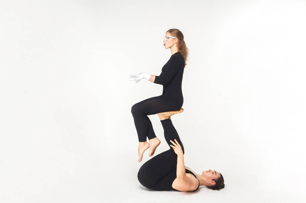 young man holding woman legs and balancing in sit pose isolated on white background, acrobatic concept  - Φωτογραφία, εικόνα