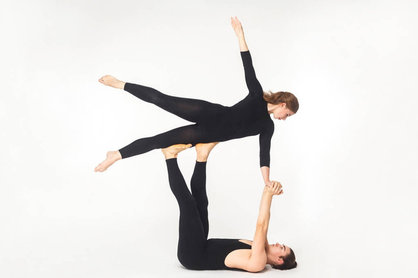 young man holding woman and balancing in fly pose isolated on white background, acroyoga concept  - 写真・画像
