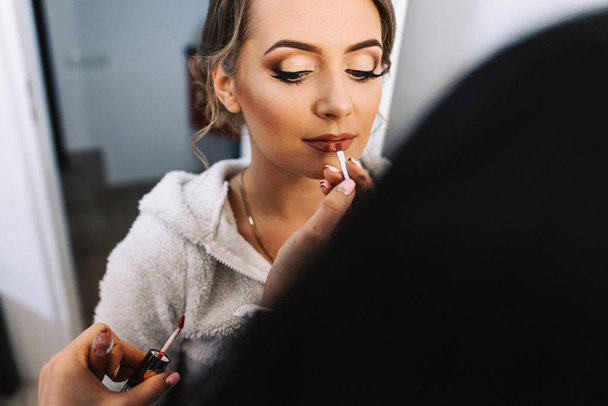 Make-up artist εφαρμόζοντας make-up για όμορφη νεαρή νύφη - Φωτογραφία, εικόνα