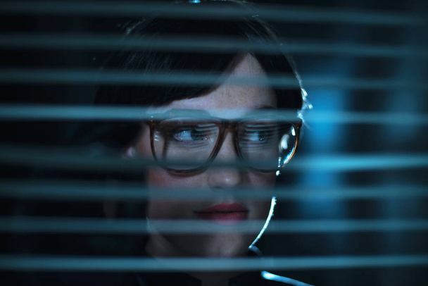 mulher de óculos olhando através de persianas
 - Foto, Imagem