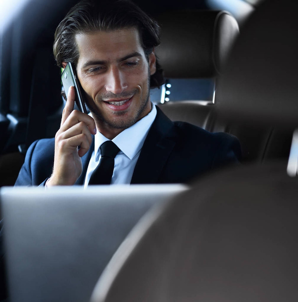 Handsome businessman using mobile phone in car. - Foto, afbeelding
