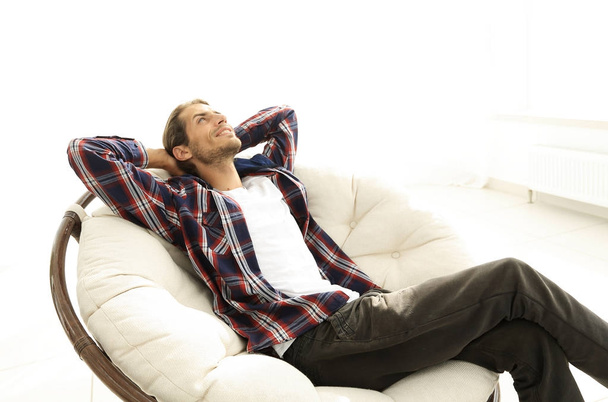 serious guy rests sitting and dreaming in a large comfortable chair. - 写真・画像