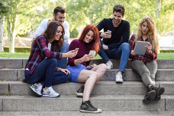 Szabadban okostelefon és a tablet számítógépeket használó fiatalok - Fotó, kép