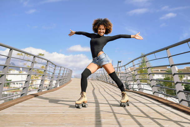 Afro hairstyle woman on roller skates riding outdoors on urban b - Foto, Bild