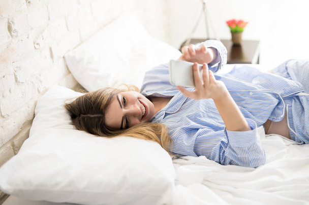 Woman in pjs using a smartphone - Photo, Image