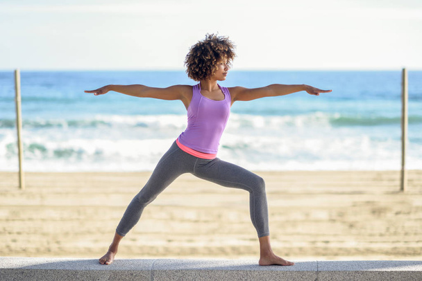Mujer negra, peinado afro, haciendo yoga en la guerrera asana en la
  - Foto, imagen
