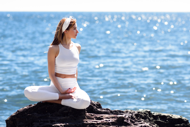 Genç kadın beyaz elbise giyen Beach yoga yaparken - Fotoğraf, Görsel