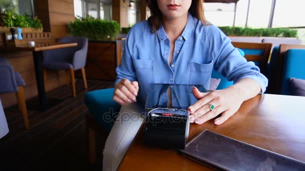 Молодая девушка вводит пин-код на магнитную карточку считывателя в ресторане
. - Кадры, видео