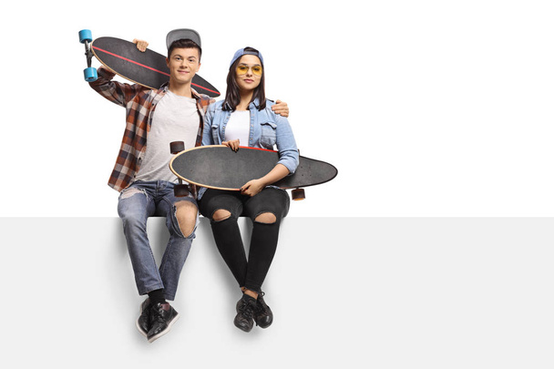 Adolescentes con longboards sentados en un panel
 - Foto, Imagen