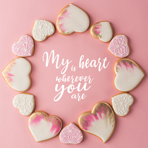 vlakke leggen met regeling van geglazuurde hartvormige cookies geïsoleerd op roze oppervlak - Foto, afbeelding