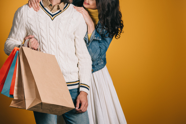 cropped image of couple with shopping bags isolated on yellow - Foto, imagen