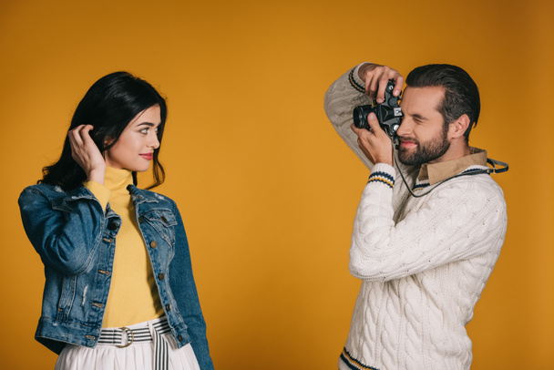 boyfriend taking photo of girlfriend with film camera isolated on yellow - Zdjęcie, obraz
