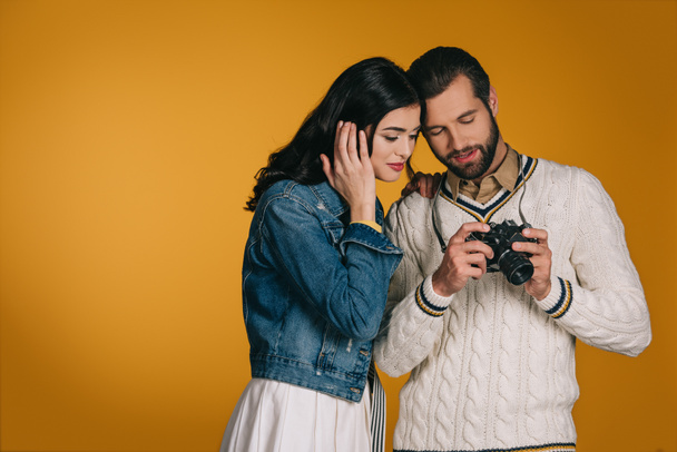 boyfriend showing film camera to girlfriend isolated on yellow - Φωτογραφία, εικόνα