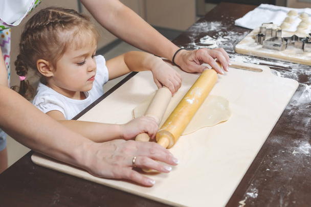 Maman montre à ses filles comment rouler la pâte pour faire des boulettes
 - Photo, image
