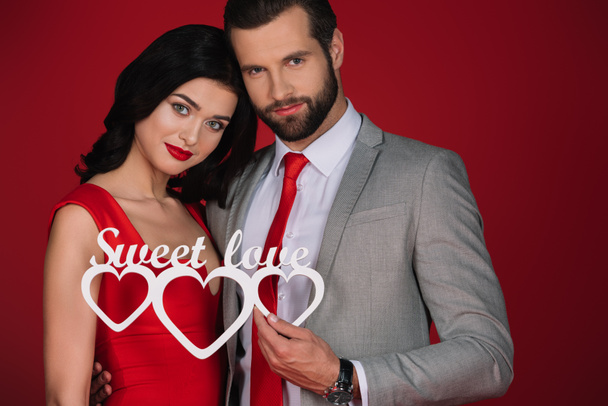 attractive couple holding sign sweet love isolated on red - Photo, Image
