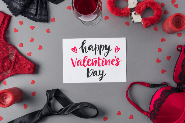 Top weergave van wit vel papier met woorden Happy Valentines Day tussen ondergoed en glas wijn  - Foto, afbeelding