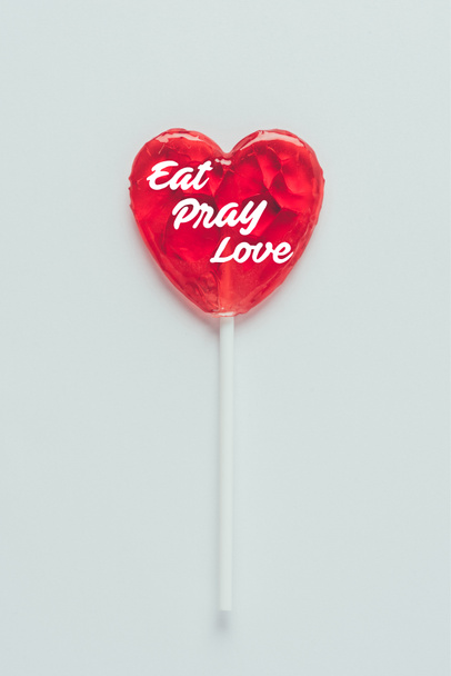 Top view of heart shaped lollipop with words eat pray love isolated on white - Photo, Image