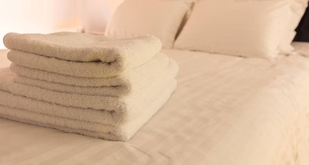 Habitación del hotel. Blanco mullido, toallas dobladas, sábanas de lino y almohadas en la cama. Vista de cerca
. - Foto, imagen