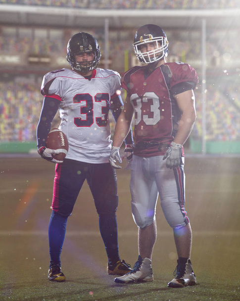 Two American football players standing  on the field of big modern stadium with flares and lights - Фото, зображення