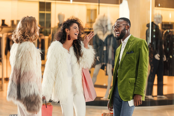 joyeuses personnes multiethniques élégantes parlant tout en faisant du shopping ensemble dans le centre commercial
 - Photo, image