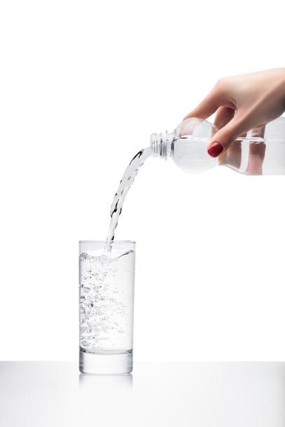 levágott lövés nő öntés tiszta víz elszigetelt fehér műanyag palackból pohárba - Fotó, kép