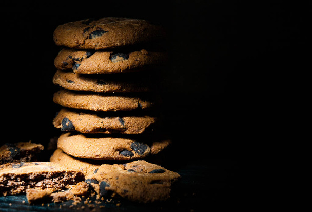 Pila de galletas de chispas de chocolate sobre fondo de madera oscura. con espacio de copia
. - Foto, imagen