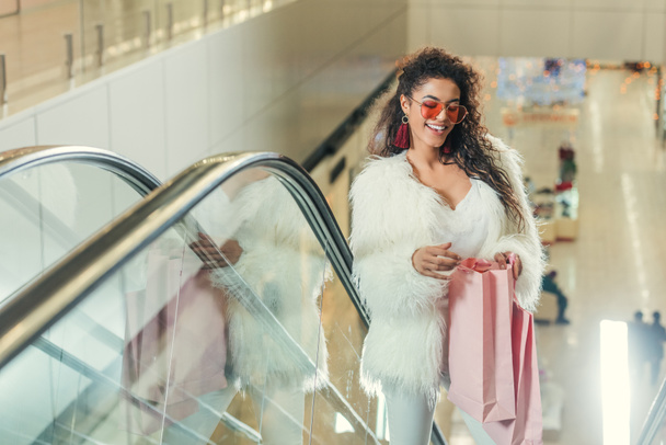 happy stylish women looking into shopping bag on escalator at mall - Фото, зображення