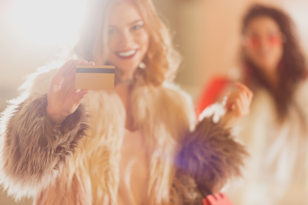 jeune femme en manteau de fourrure avec carte de crédit dorée sur les achats
 - Photo, image