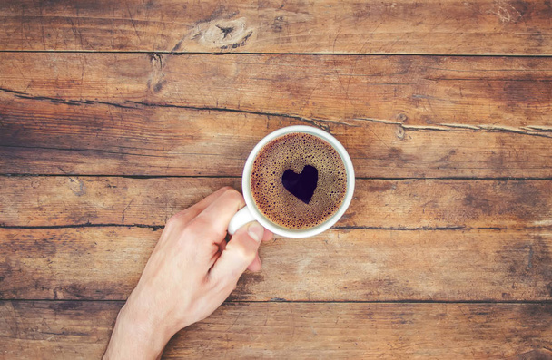 Tasse Kaffee in den Händen eines Mannes. Herz aus Schaum. Selektiver Fokus. - Foto, Bild