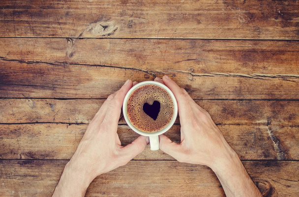 Tasse Kaffee in den Händen eines Mannes. Herz aus Schaum. Selektiver Fokus. - Foto, Bild