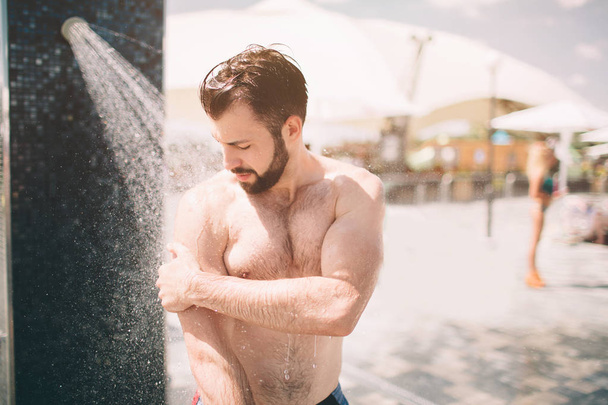 Handsome man taking a shower on the beach. - Фото, зображення