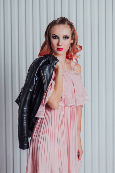 Beautiful young woman with pink hair in leather jacket posing in studio. - Фото, зображення