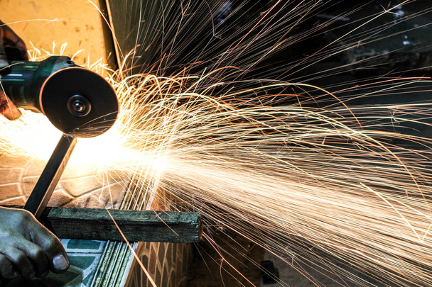  Worker cutting metal with grinder. Sparks while grinding iron - Photo, Image