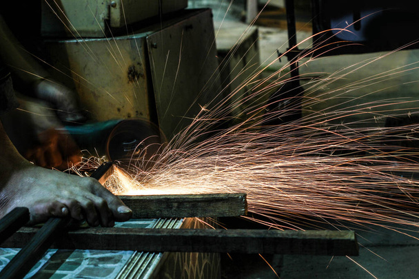  Robotnik obcinający metal szlifierką. Iskry podczas mielenia żelaza - Zdjęcie, obraz