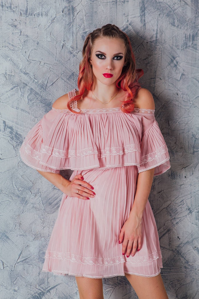 Beautiful young woman with pink hair and dress posing in studio. - Фото, зображення