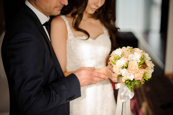 bride and bridegroom looking together at the bouquet of roses - Photo, Image