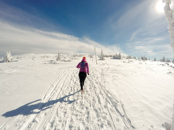Running vrouw op winter trail, de sneeuw en de witte bergen - Foto, afbeelding