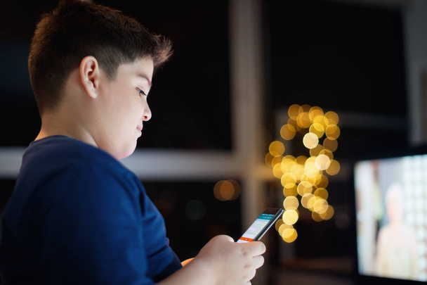 Αφύλακτο αγόρι κουβεντιάζοντας και πληκτρολογώντας στο κινητό τηλέφωνο το βράδυ - Φωτογραφία, εικόνα