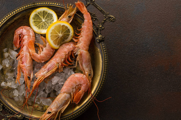 Large tiger Shrimps and slice of lemon fresh in ancient plate full of ice. - Photo, image