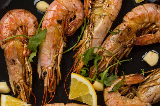 prawns shrimps with garlic, lemon, spices and italian parsley garnish in a black pan on white painted rustic wood, selected focus, narrow depth of field - 写真・画像