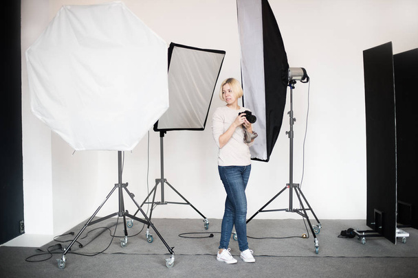 backstage to photoshooting in studio with professional lighting equipment, photographer looking at the pictures from camera display - Фото, зображення