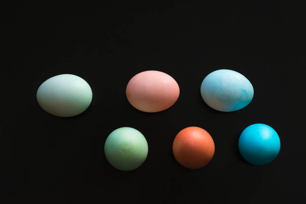Easter eggs are placed in a design and placed on a black surface - Photo, Image