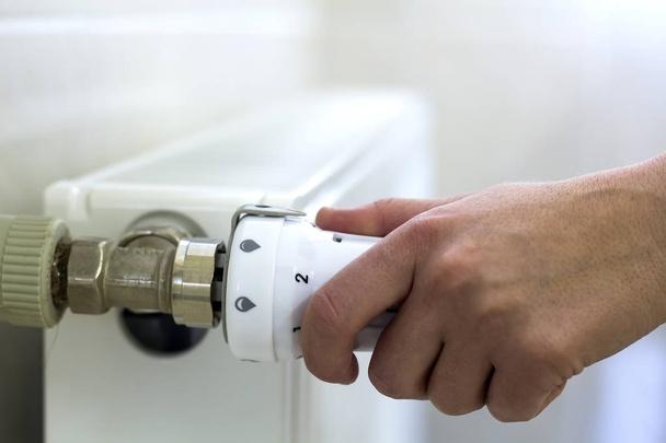 Käsi säätämällä venttiilin nuppi termostaatti lämmityspatterin
 - Valokuva, kuva