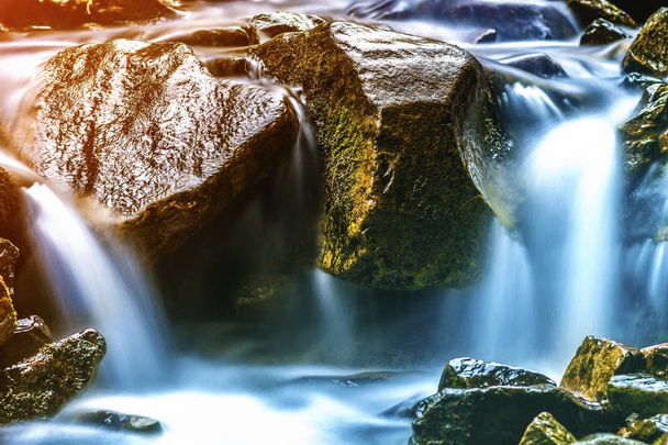 Mały wodospad z niebieski pienista woda na mokrych kamieniach - Zdjęcie, obraz