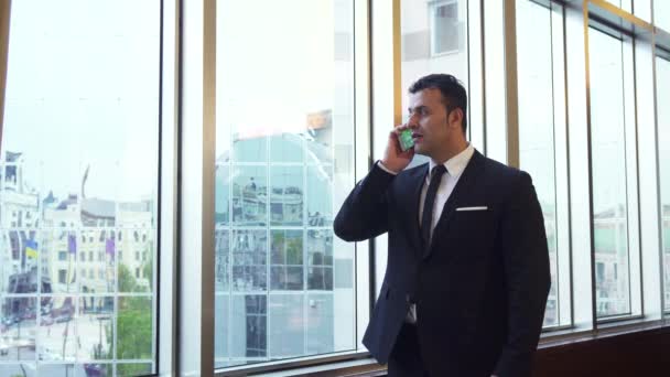 Business man takes a phone call and looks at his wrist watch - Imágenes, Vídeo