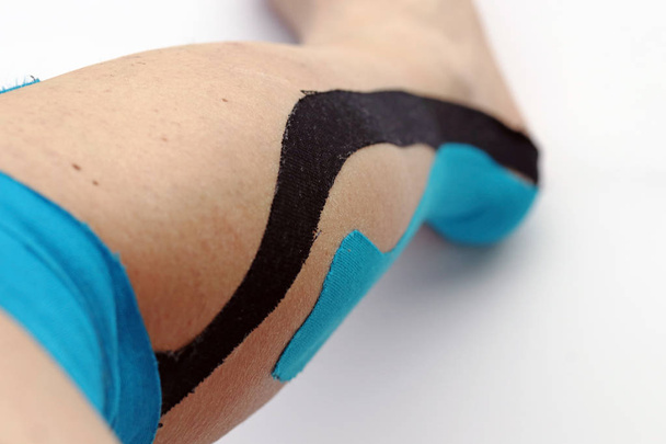 Tape pleister op een vrouw been. Kinesio tape op de been. Tape plakband voor sportgeneeskunde - Foto, afbeelding