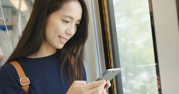 Kobieta za pomocą telefonu komórkowego, w pociągu  - Zdjęcie, obraz